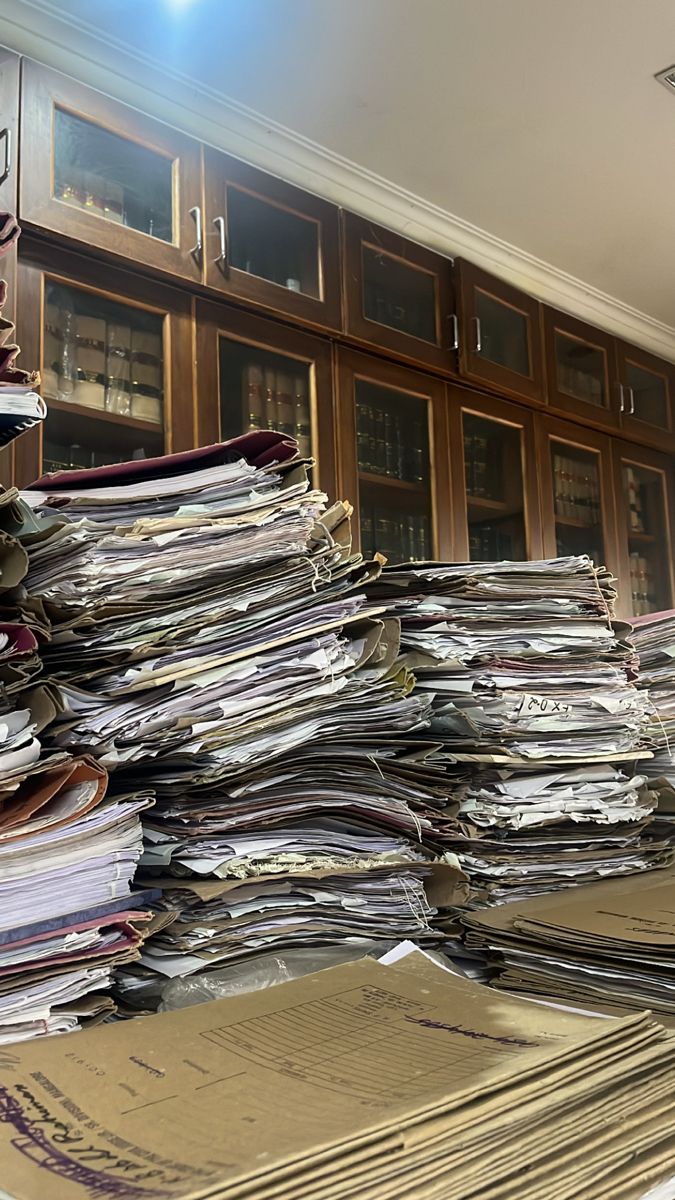 a large stack of papers sitting on top of a table next to a bookshelf