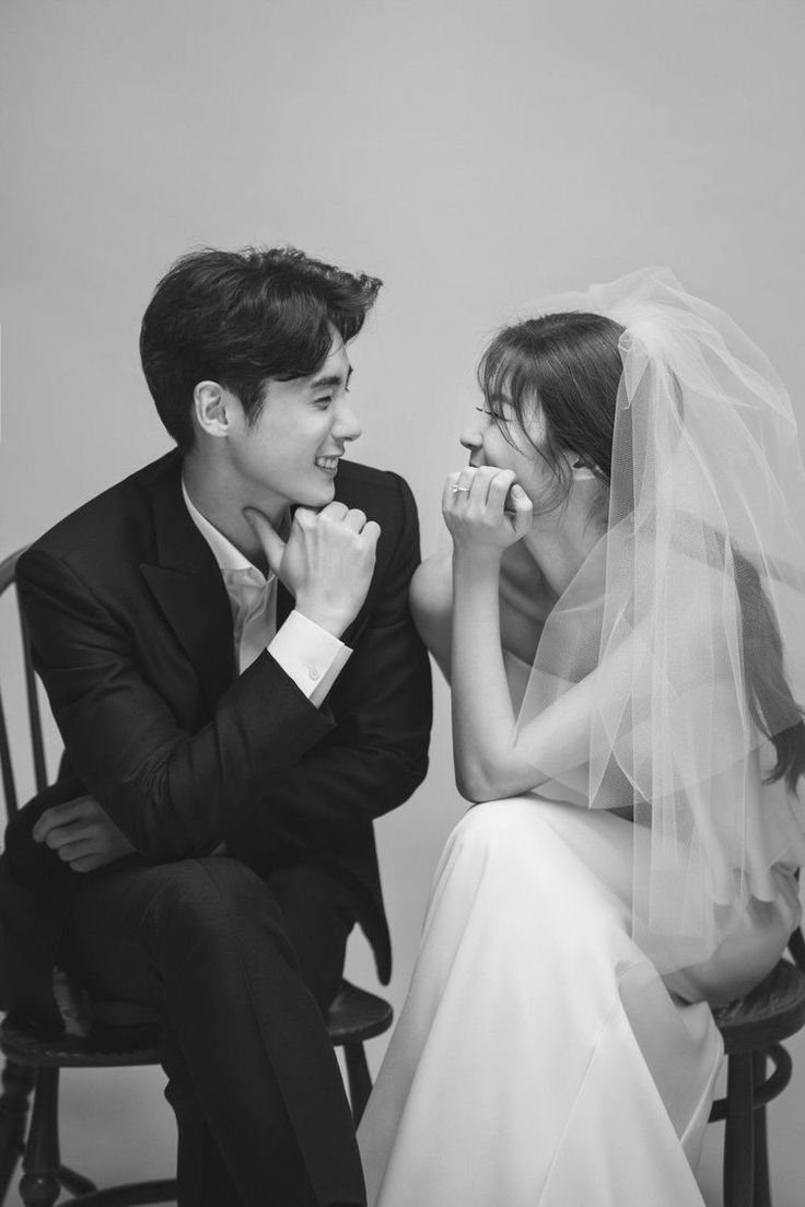 a man and woman sitting next to each other on a chair with their hands in their mouths