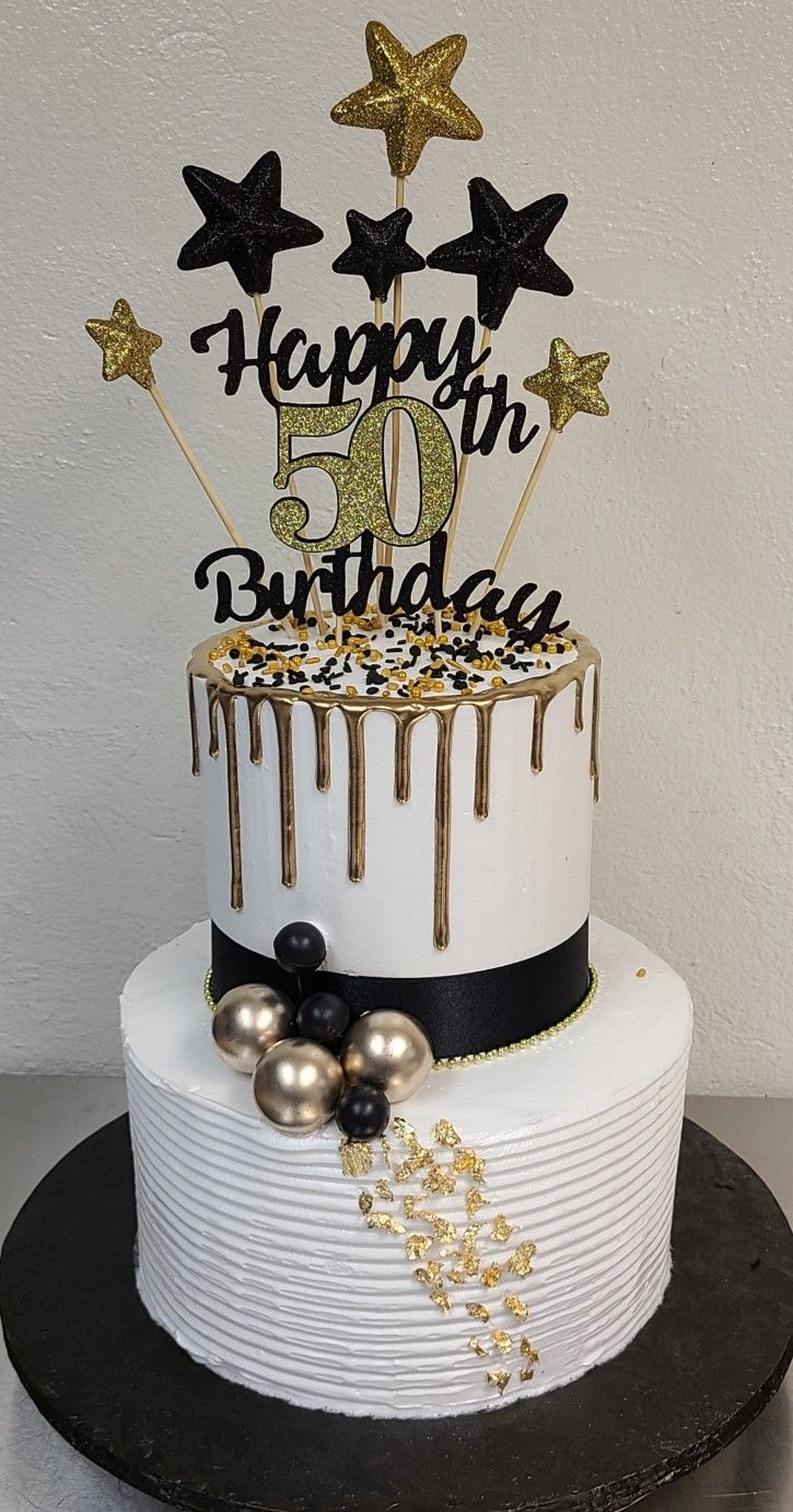 a white and black birthday cake with gold stars on top that says happy 50th birthday