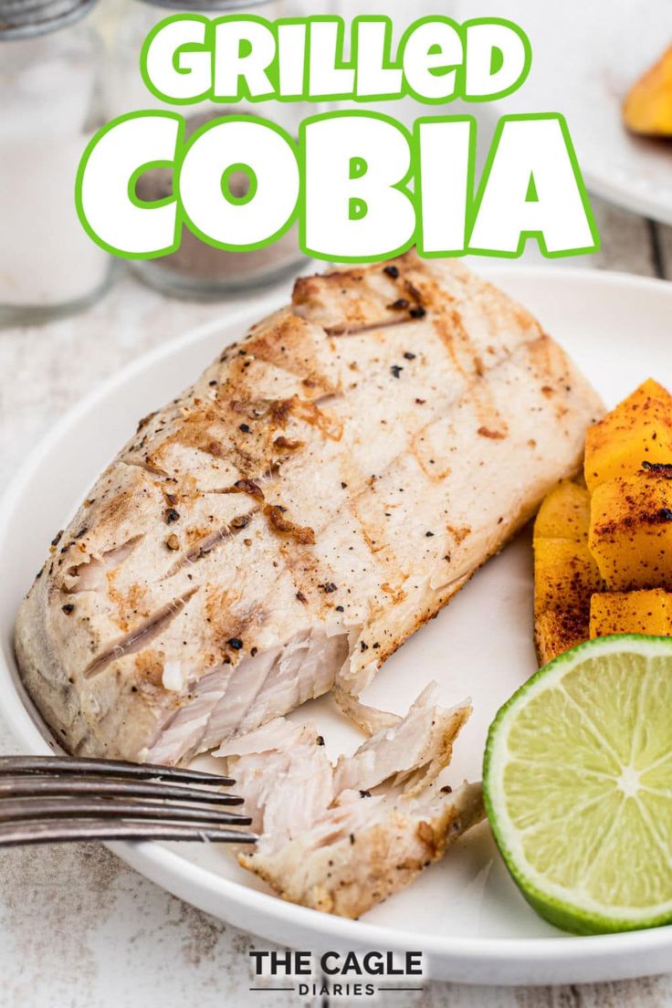 grilled cobia on a white plate with lime wedges and sliced pineapple