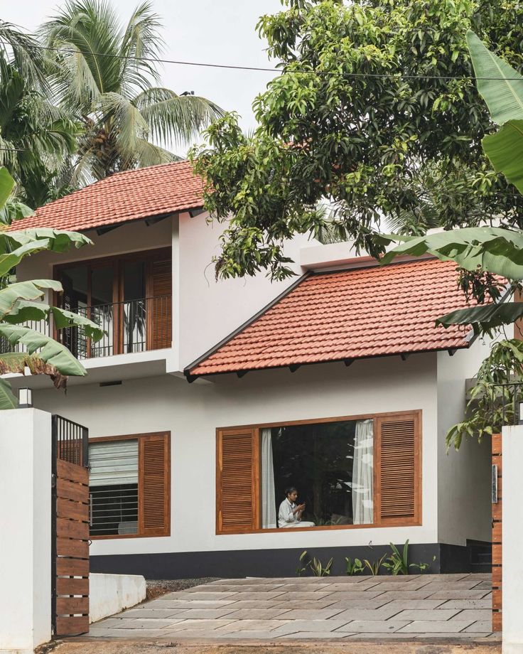 a white house with wooden shutters on the front and side windows, surrounded by trees