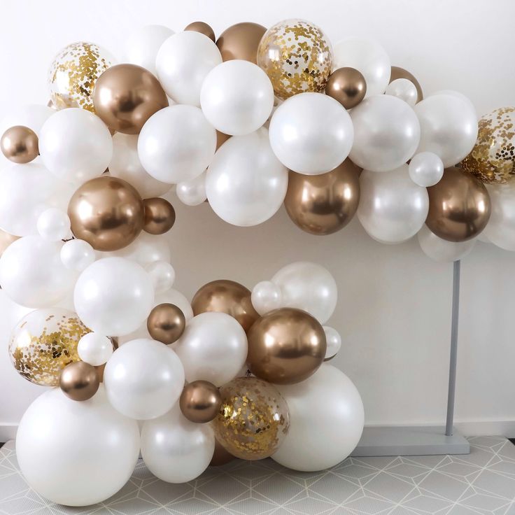 white, gold and silver balloons are arranged in the shape of the letter o on a table