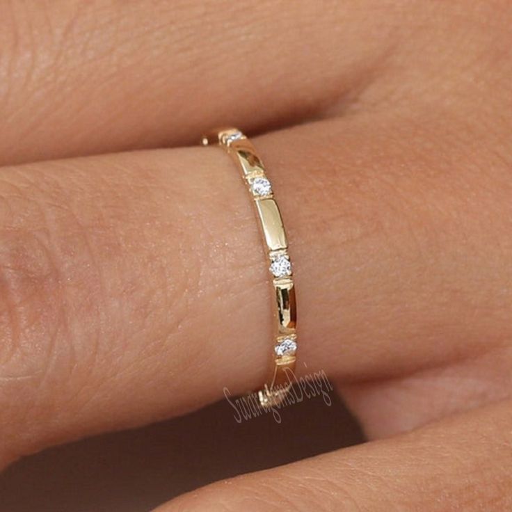 a close up of a person's hand wearing a gold ring with diamonds on it