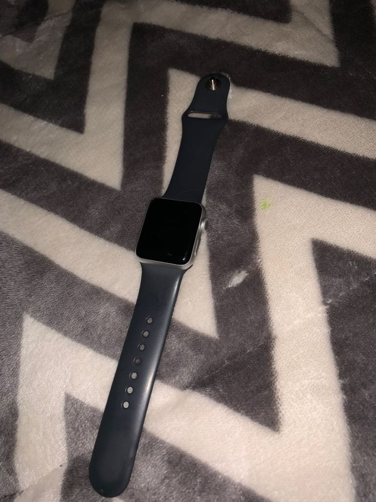 an apple watch sitting on top of a white and black carpeted floor next to a cell phone