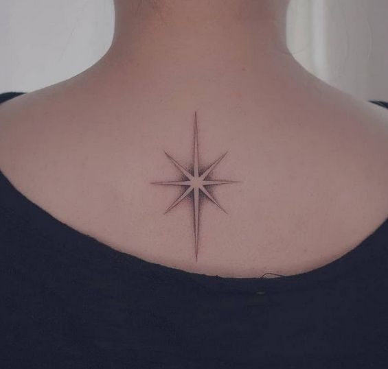 a woman with a star tattoo on her back shoulder and neck is looking at the camera