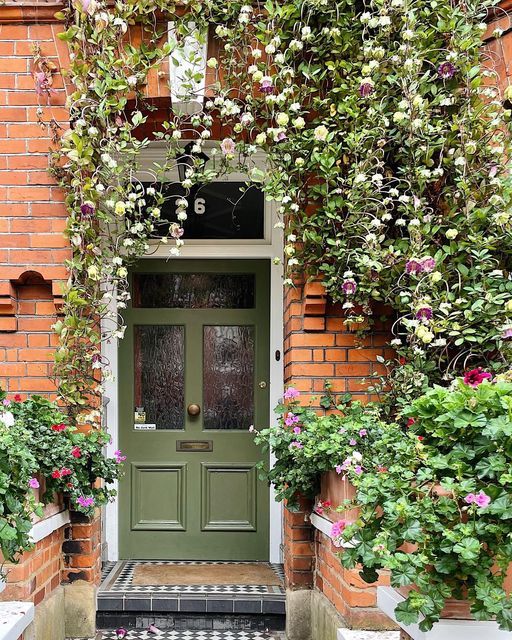 a green door surrounded by plants and flowers