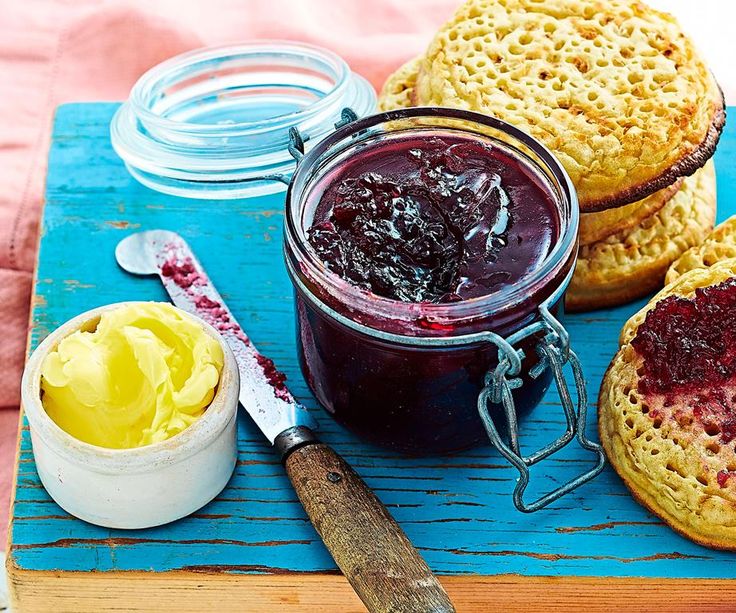 jam in a jar next to two biscuits and a knife on a blue cutting board