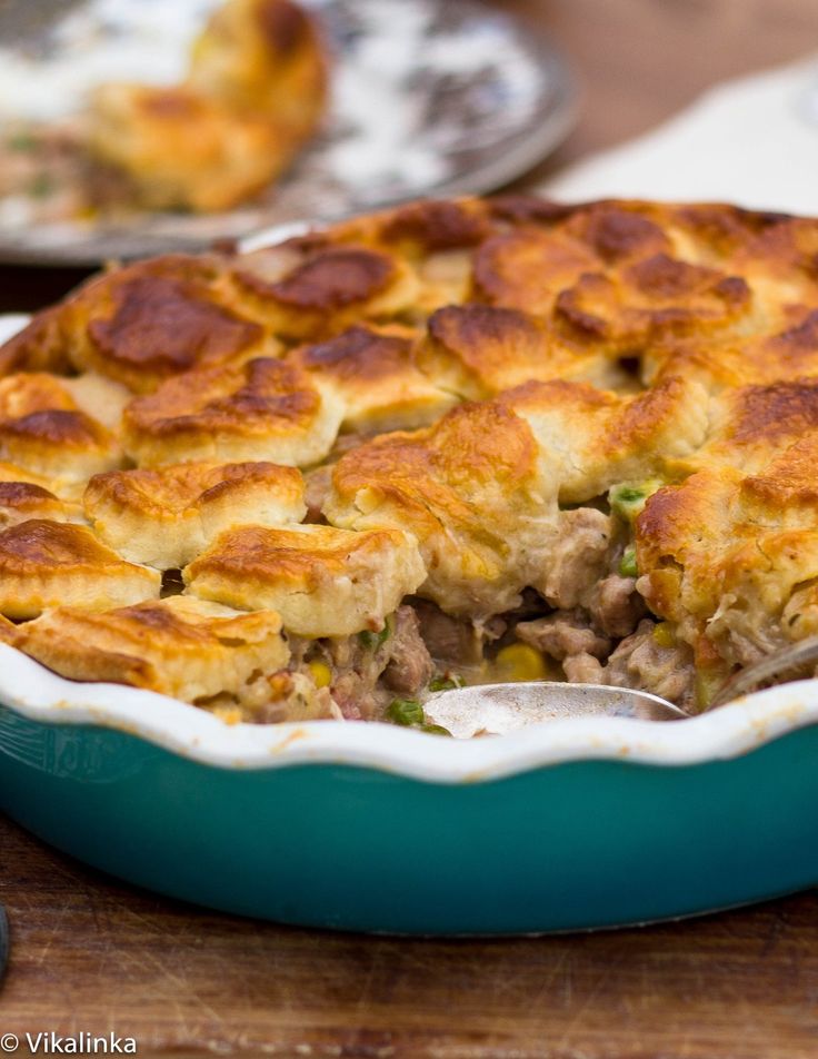 a casserole dish with meat and vegetables in it on a cutting board next to silverware