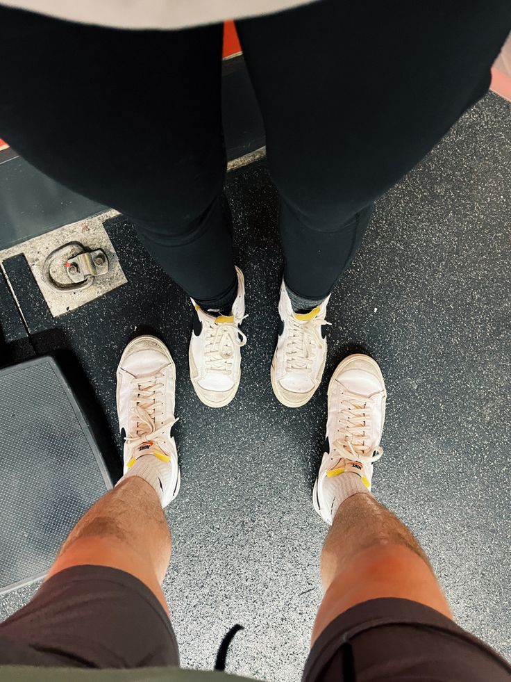 two people standing next to each other in front of a weight machine with their feet up