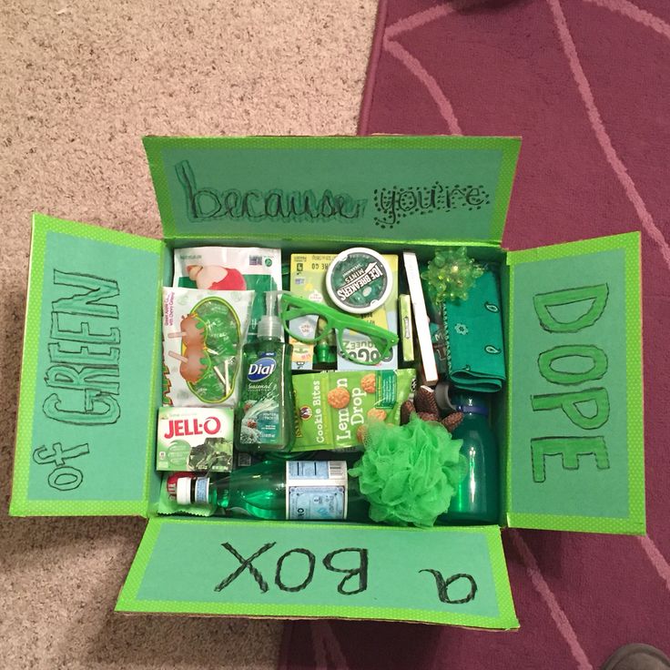 an open green box with various items inside on the floor next to a person's feet