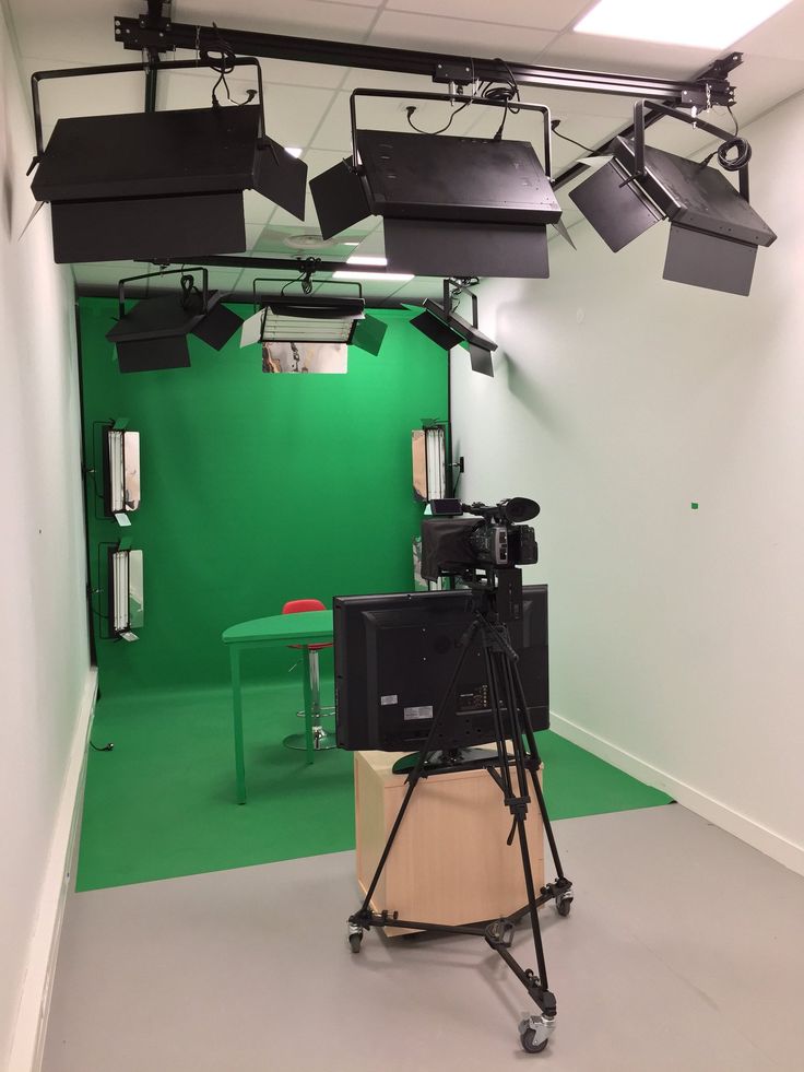 an empty room with green screen and lights on the ceiling, set up for filming