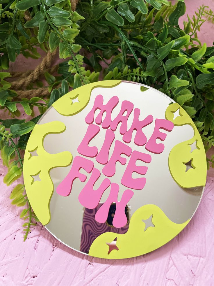 a mirror with the words bake life fun painted on it next to some plants