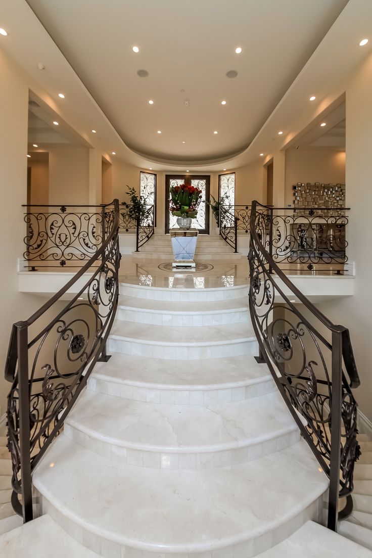 a staircase leading up to the second floor in a house with white marble steps and railings