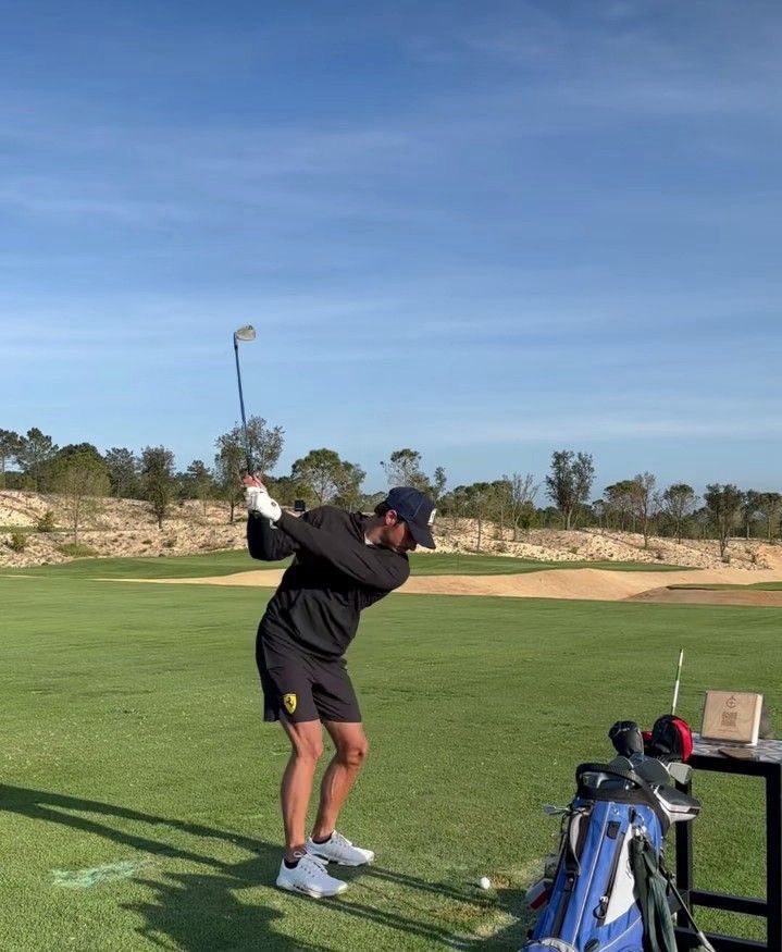 a man in black shirt and shorts playing golf