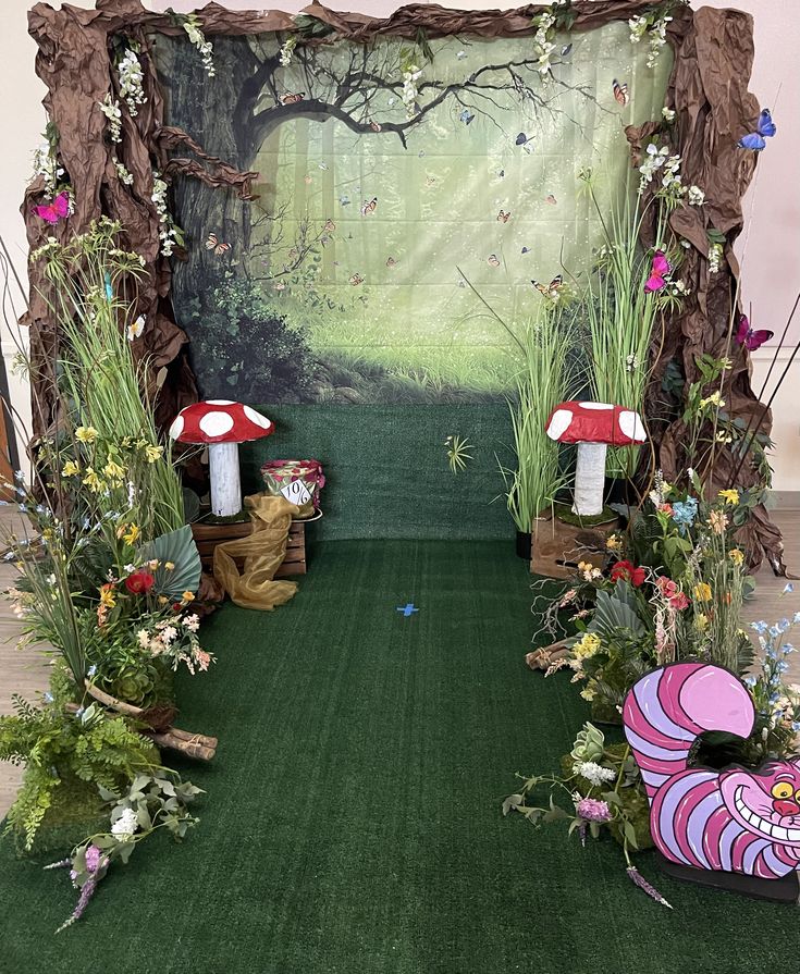 a green carpeted area with fake mushrooms and flowers on the ground, in front of a fairy scene