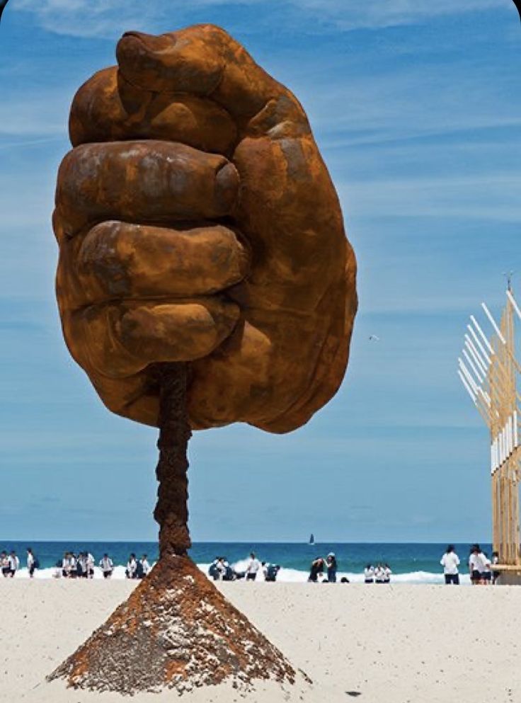 a large hand sculpture on top of a sandy beach