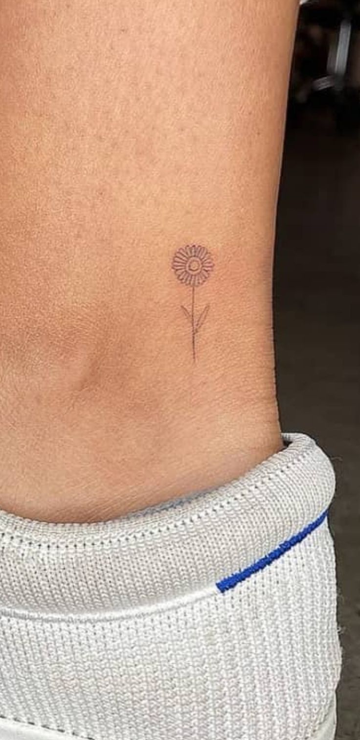 a small flower tattoo on the back of a woman's stomach