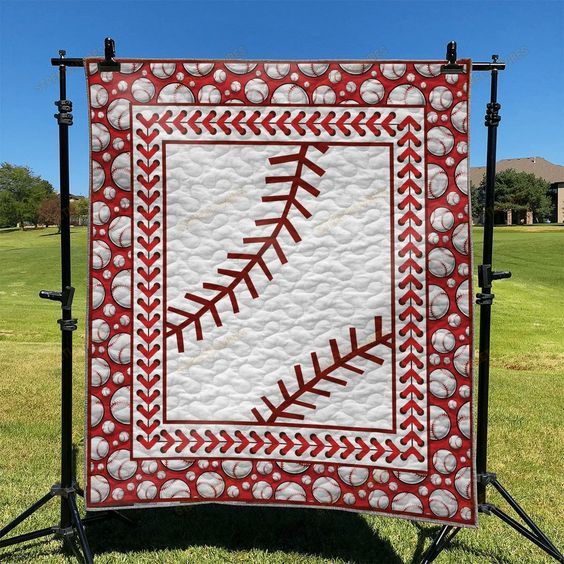 a red and white quilt with a baseball in the center on a black tripod