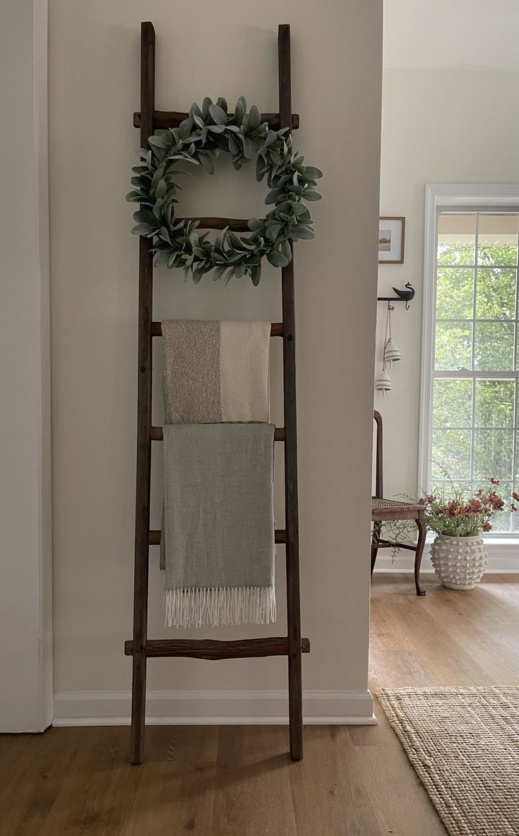 a wooden ladder with a wreath on top of it next to a wall mounted towel rack