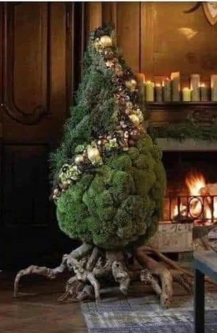 a christmas tree made out of moss and lit candles in front of a fire place