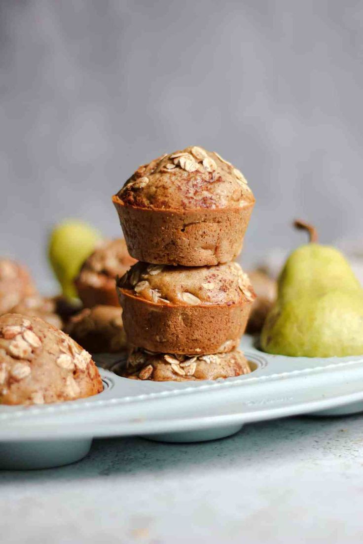 three muffins stacked on top of each other with pears in the background