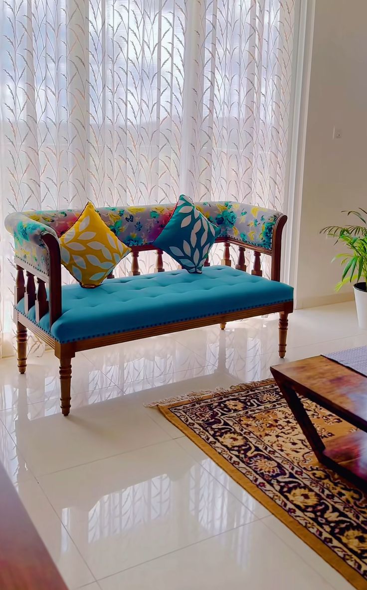 a blue couch sitting in front of a window next to a table with a potted plant on top of it