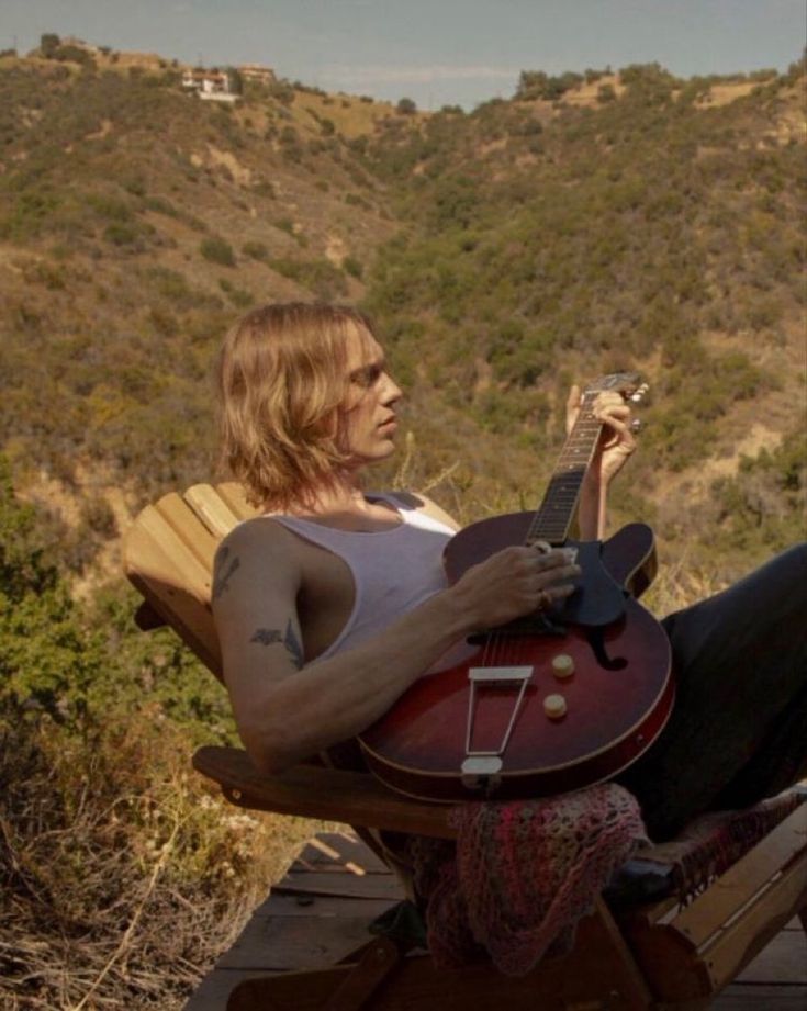 a woman sitting in a chair holding a guitar