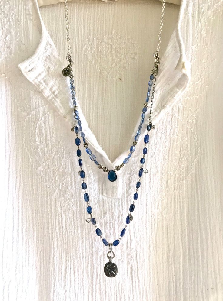 this beautiful gemstone double strand necklace is a perfect london blue navy thats great with blue jeans! it's bottom strand is a beaded rosary-style chain of london blue topaz- with little heart & flower charms on the sides- in the center is a circular oxidized pewter flying fairy pendant with the word "joy" on the back! the upper strand is a beaded chain of navy blue topaz oval beads with silver thai rose beads that meets in the center with a navy london blue topaz teardrop briolette! these strands meet at the sides with artisan silver plated square cross connectors, held by a long sterling silver chain. it has a heart lobster clasp and hangs very long, a few inches under bra line! beautifully adorns any outfit doubly! especially lovely with jeans! falls 34 inches long, under bra line AL Jojo Jewelry, Flying Fairy, Jean Genie, Collar Rosa, Triple Layer Necklace, Rose Beads, Vintage Jewelry Ideas, Word Joy, Beaded Rosary