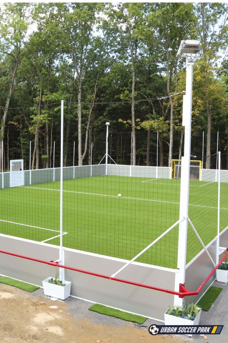 an outdoor tennis court surrounded by trees and grass with red lines on the sidelines