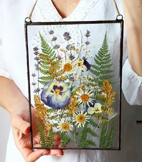 a woman holding up a painting with flowers on it