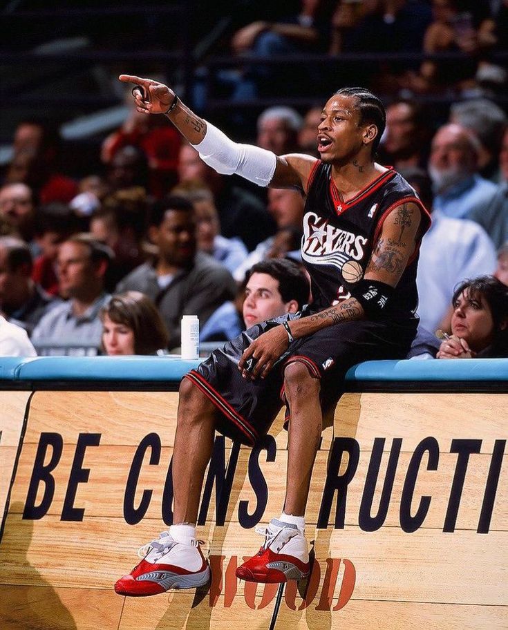 a man sitting on top of a wooden bench in front of a group of people