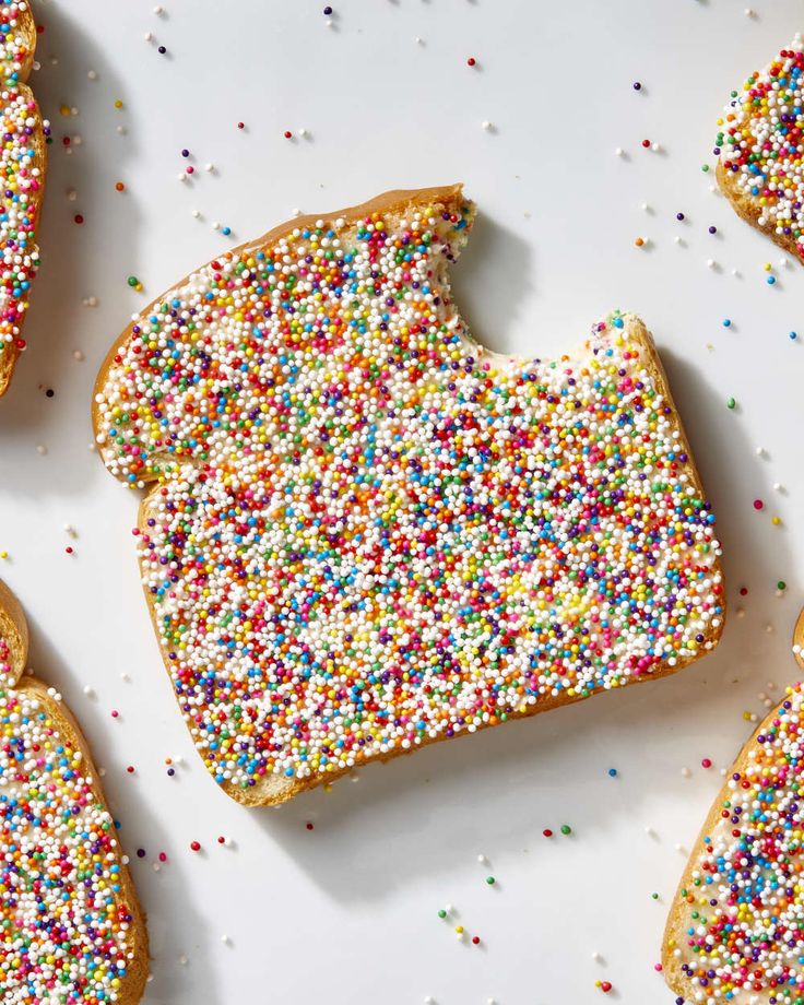 sprinkle covered cookies are arranged on a white surface with multicolored sprinkles