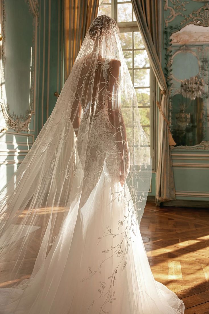 the back of a bride's wedding dress in front of a window