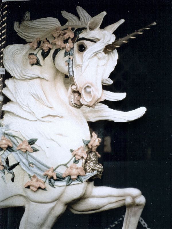 a statue of a white horse with flowers on it's head and manes