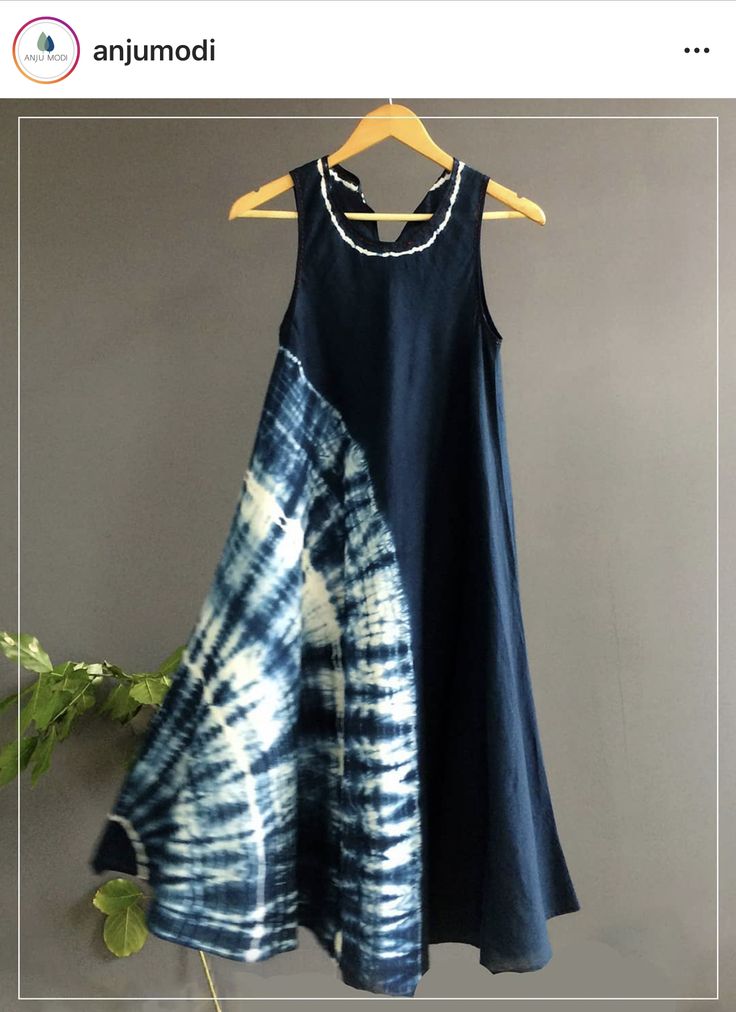 a blue and white dress hanging on a hanger next to a potted plant