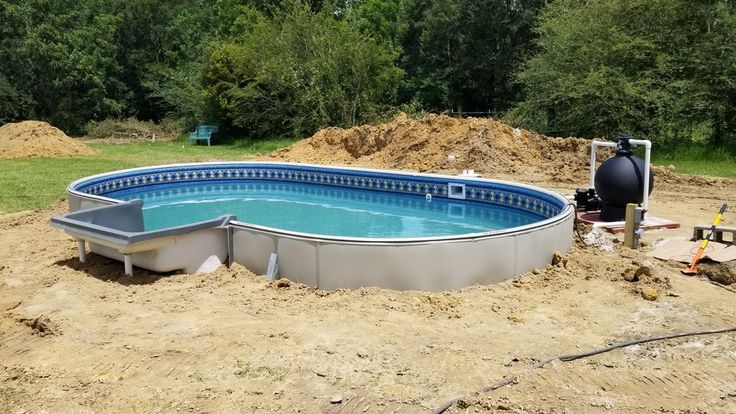 an above ground swimming pool being built in the middle of a field with dirt surrounding it