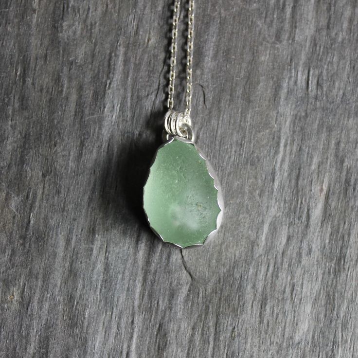 Do you need a great gift for your mom or grandma? Do you want to be reminded of a trip to the ocean? This is a sterling silver sea foam green sea glass necklace that would make a perfect gift for a friend or relative who is hard to buy for. Here are the details:This necklace has a piece of rare sea foam green green sea glass with a large air bubble in the center. It is set in a scalloped bezel with a simple bail. And, it will arrive to you on an 18” sterling silver chain. All of my sea glass is found and not altered in any way and this piece of sea glass is from a beach in the UK. All of our sea glass jewelry was handmade by Barb Macy in Corvallis, OR. Sea Glass Large Pendant Necklace, Unique Handmade Sea Glass Necklaces, Handmade Unique Necklace With Sea Glass, Silver Teardrop Sea Glass Jewelry, Natural Stone Necklaces With Recycled Glass For Gifts, Natural Stones Necklace With Recycled Glass For Gifts, Gift Necklaces With Natural Stones And Recycled Glass, Handmade Silver Recycled Glass Necklace, Handmade Silver Necklace With Recycled Glass