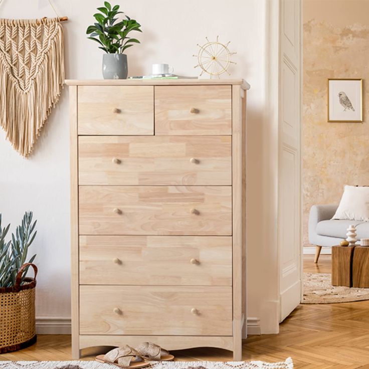 a wooden dresser sitting in a living room next to a white chair and potted plant