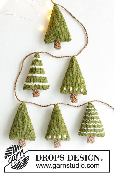 knitted christmas trees are hanging from string with lights in the shape of pine cones