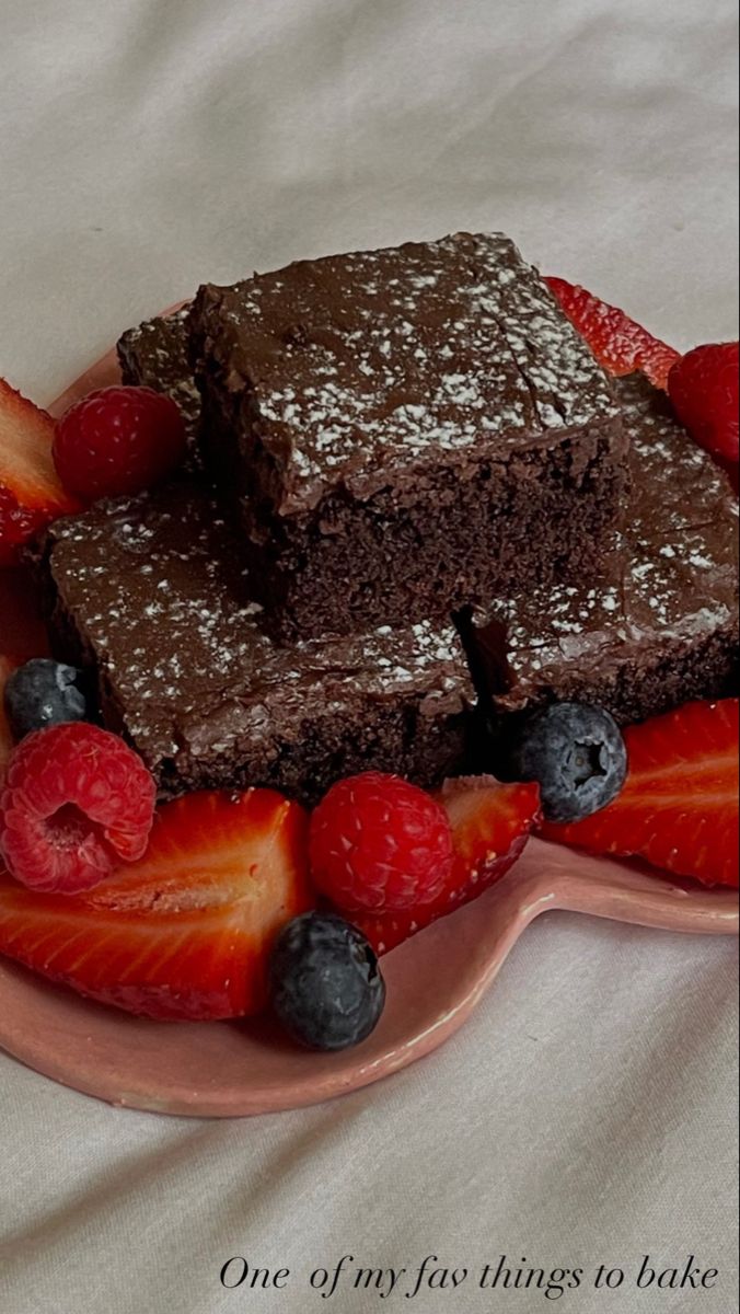 two pieces of chocolate cake on a plate with strawberries and blueberries