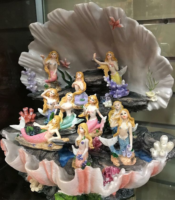 a group of little mermaid figurines sitting on top of a shell in a display case