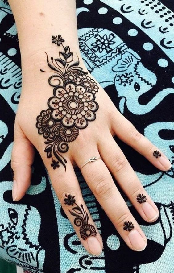 a woman's hand with henna tattoos on it and a flower tattoo on the wrist