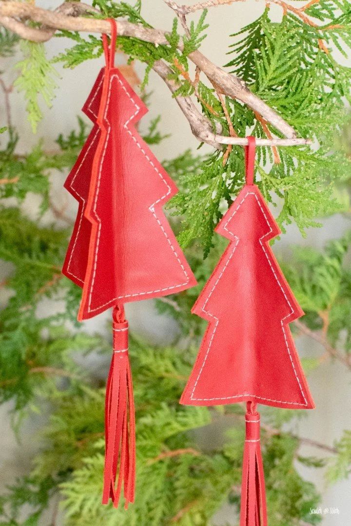 two red leather christmas trees hanging from a tree branch