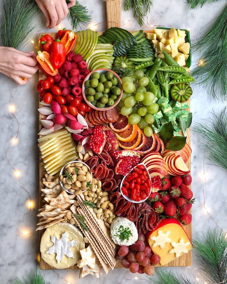 a wooden cutting board topped with lots of different types of fruits and veggies