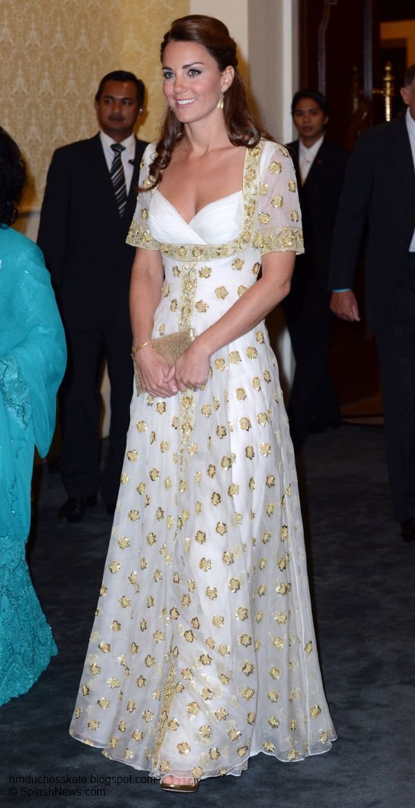 a woman in a white and gold dress smiles as she walks with other people behind her