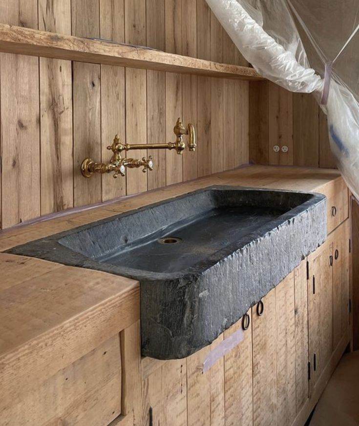 a large stone sink in the corner of a room with wooden walls and flooring