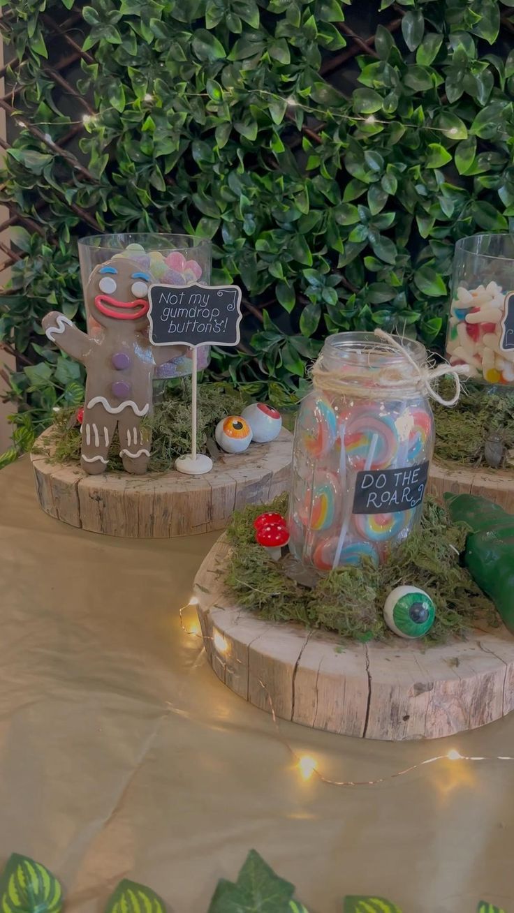 two jars with candy and candies are on display in front of some bushes,