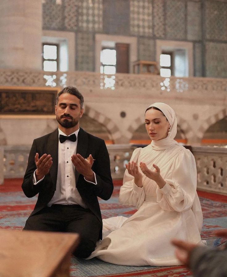 a man and woman sitting on the floor in prayer with their hands together, while wearing turbans