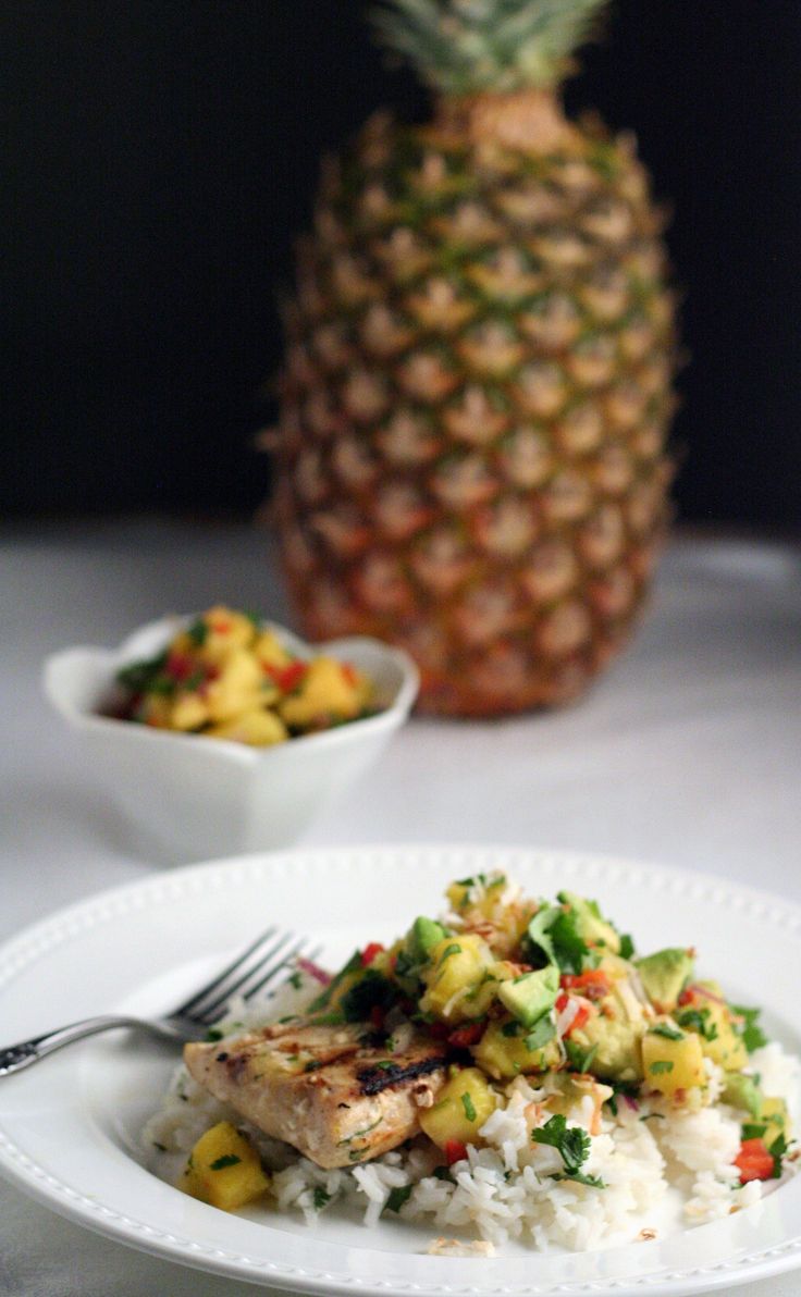 a white plate topped with rice and vegetables next to a pineapple on a table