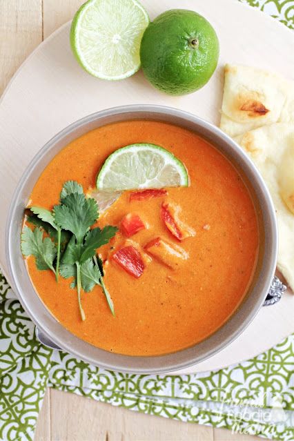 there is a bowl of soup with limes on the side and pita bread